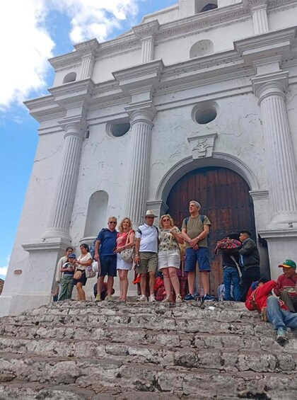 A group of people standing in front of a white colonial-style building with a large wooden door. 4