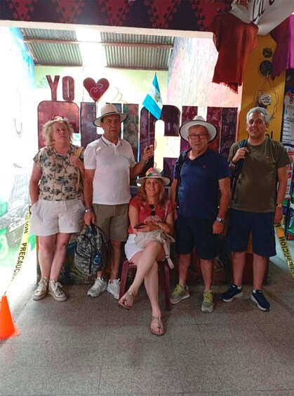 A group of people standing in front of a colorful backdrop with the word 'YOLO' and a heart symbol. 5