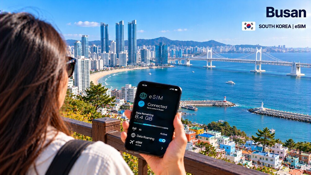 A person holding a smartphone with a cityscape and a bridge in the background. 5
