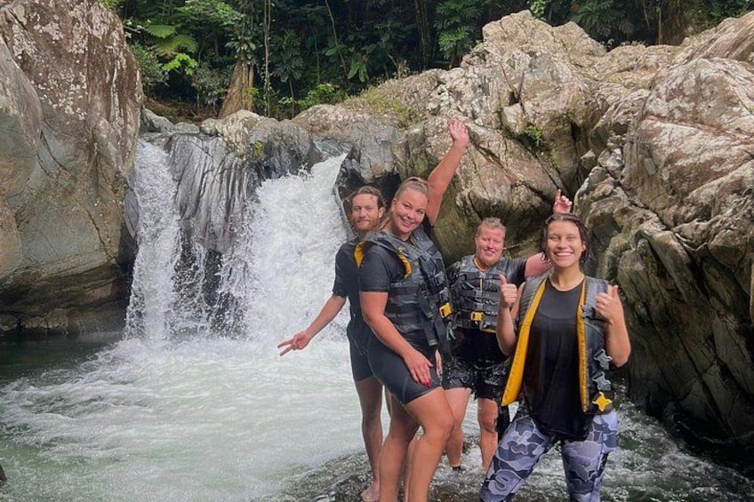 Un grupo de personas con trajes de neopreno cerca de una cascada en una zona rocosa. 1