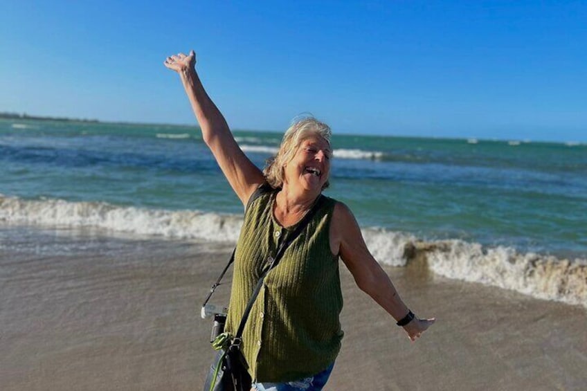 A person standing on a sandy beach with waves in the background. 4