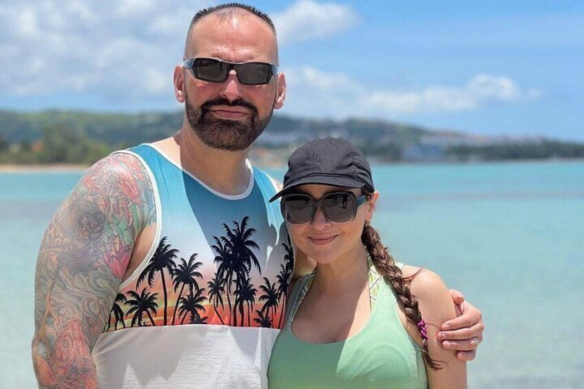 Un uomo e una donna in piedi su una spiaggia con acque blu cristalline e una costa in lontananza. 5