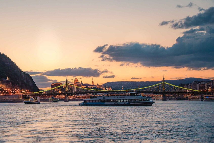 A sunset over a river with a bridge, boats, and cityscape. 3