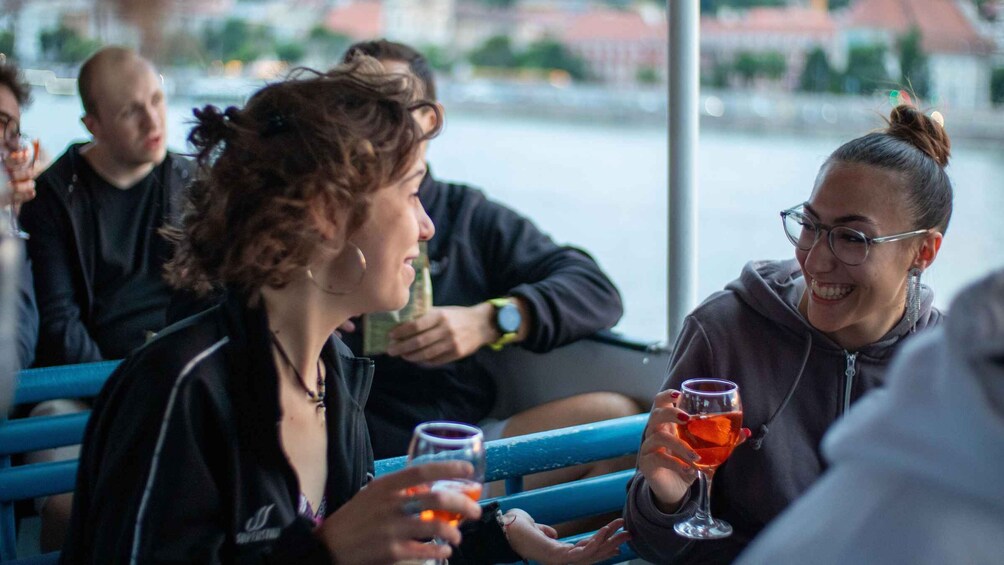 People sitting on a boat with drinks, a river in the background. 5