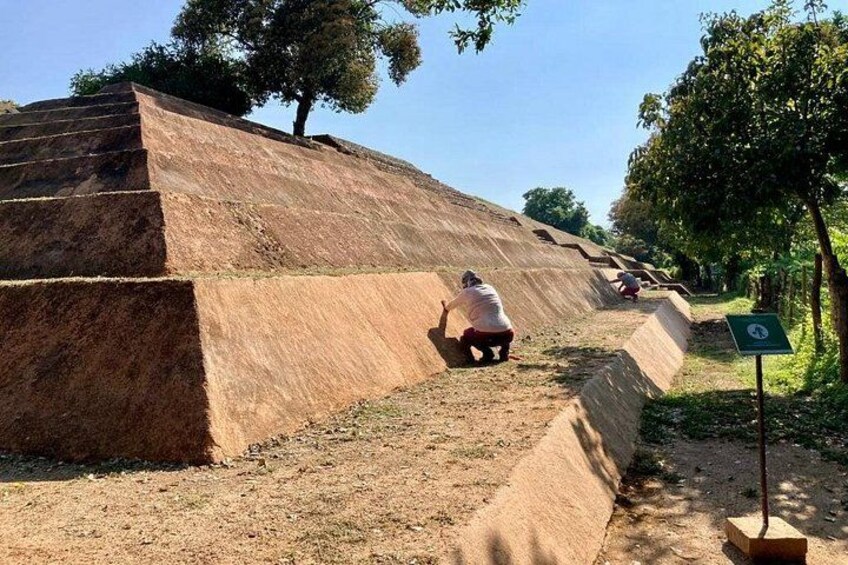 A person climbing a steep, sandy slope with a tree in the background. 1