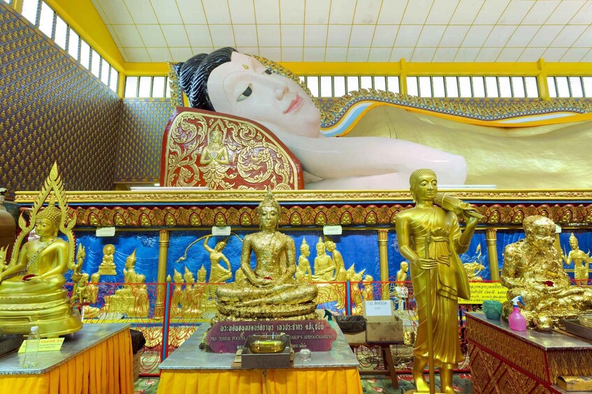 Temppelin sisätilat, joissa on kultaisia patsaita, mukaan lukien maassa makaava Buddha-patsas ja suuri Buddha-päänmuotoinen patsas. 2