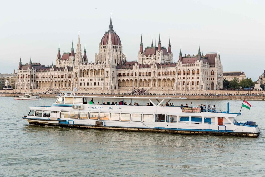 A boat with passengers in front of a large, ornate building with multiple spires. 3
