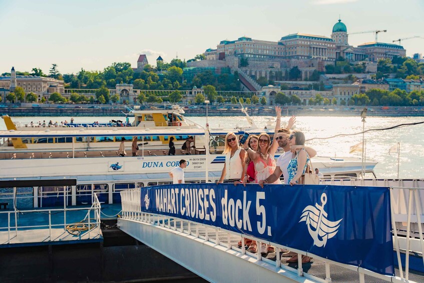 A cruise ship docked at Mahart Cruises dock 5 with passengers on the deck. 5