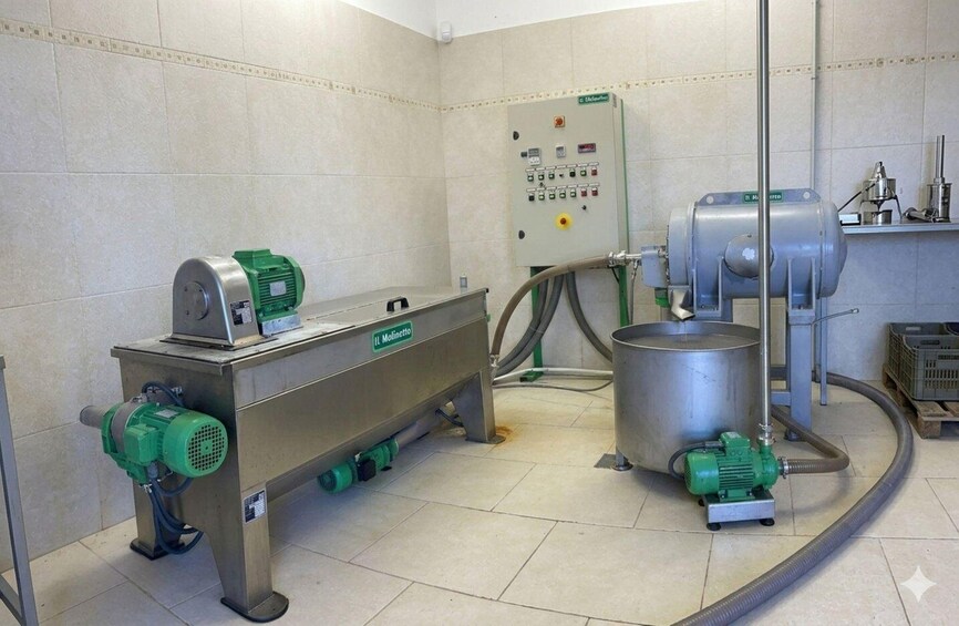 A stainless steel industrial machine with a control panel, green motors, and a large metal container. 3
