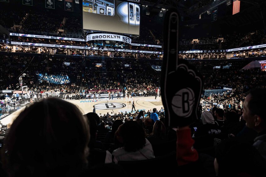 A basketball game in a crowded arena with a scoreboard and advertisements. 5