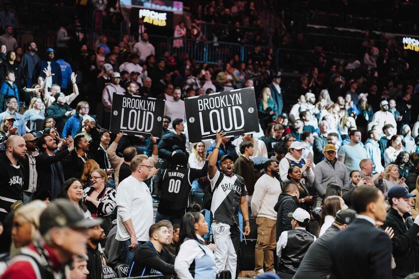 A crowd of people at a sports event, holding signs that read 'BROOKLYN LOUD'. 3