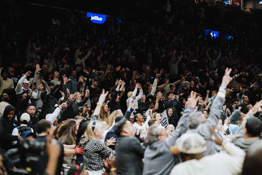 A crowded indoor event with people raising their hands. 2