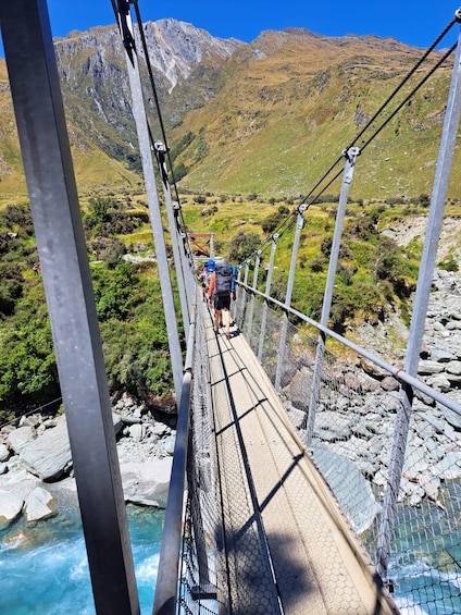 A suspension bridge over a river with hikers on it. 5