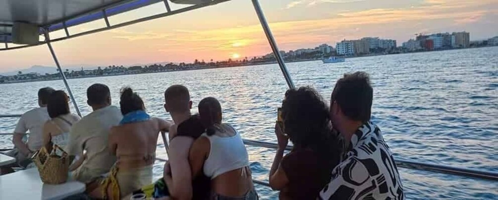 A group of people on a boat during sunset. 4