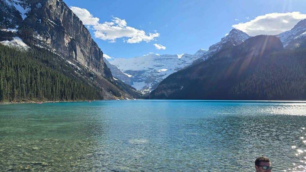 A clear lake surrounded by mountains with snow-capped peaks and dense forests. 5
