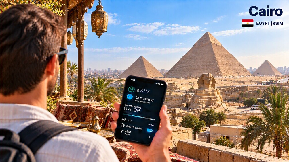 Eine Person hält ein Smartphone mit eSIM-Verbindung in Kairo, Ägypten, mit Pyramiden und der Sphinx im Hintergrund. 5