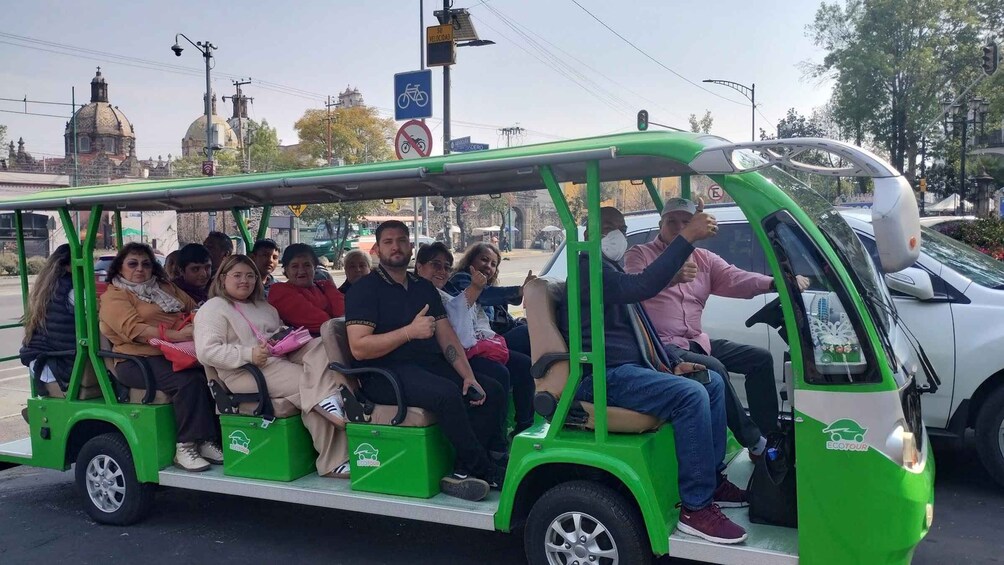A green electric tour vehicle with passengers. 3
