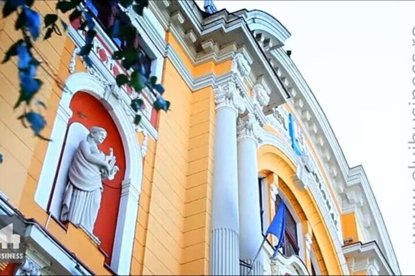 Un edificio con architettura elaborata, tra cui una statua, un portone rosso e colonne. 4