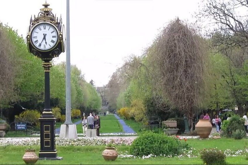 Un parco con una grande torre dell'orologio, sentieri e persone che passeggiano. 5
