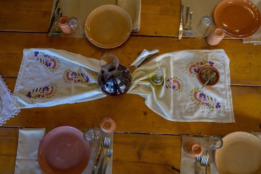 A wooden table set for a meal with plates, cutlery, and a decorative cloth. 2