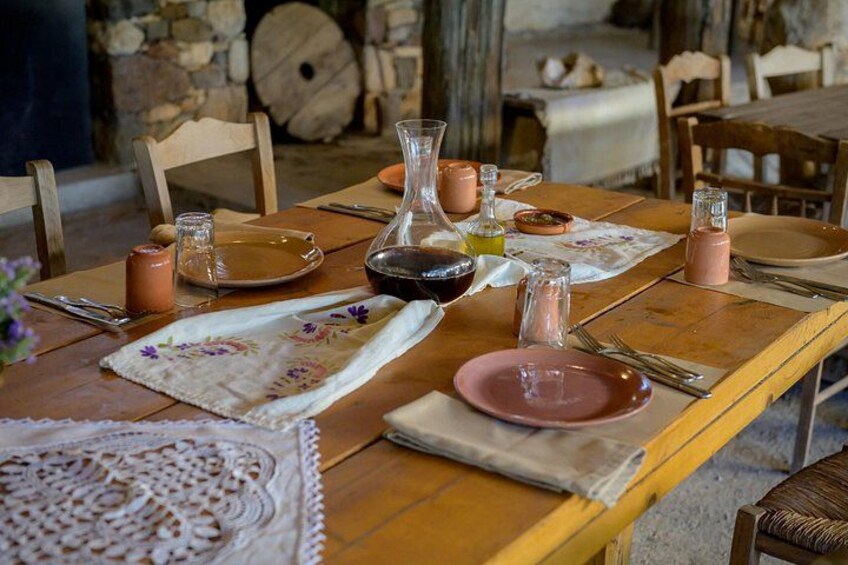 A wooden table set for a meal with plates, cutlery, a pitcher, and a glass. 3