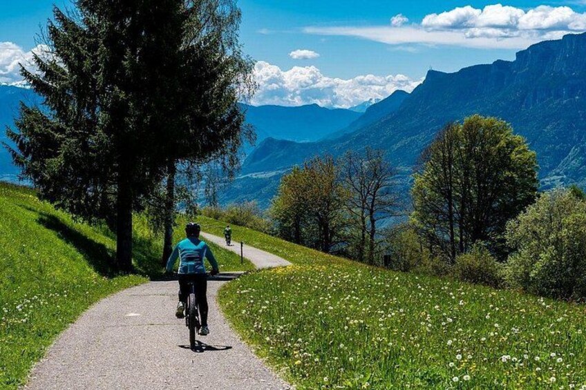 Une personne à vélo sur un chemin pavé, entourée de verdure et de montagnes. 5
