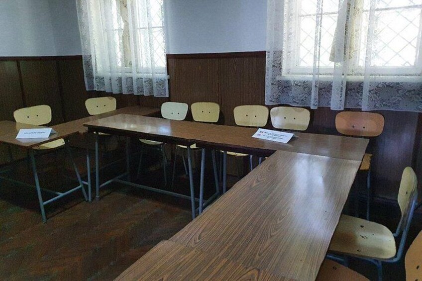 Un salón de conferencias con una larga mesa de madera y varias sillas. 3