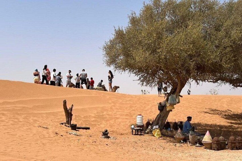 A group of people gathered around a tree in a desert landscape. 3