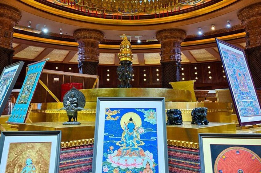 A temple interior with ornate columns, a central statue, and framed artwork. 2