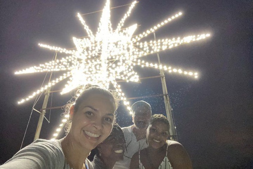 A person taking a selfie with a large, illuminated star-shaped light decoration in the background. 1