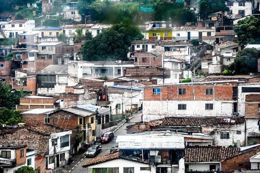 A densely packed urban area with numerous buildings, some with visible signs and advertisements, and a street with parked cars. 5