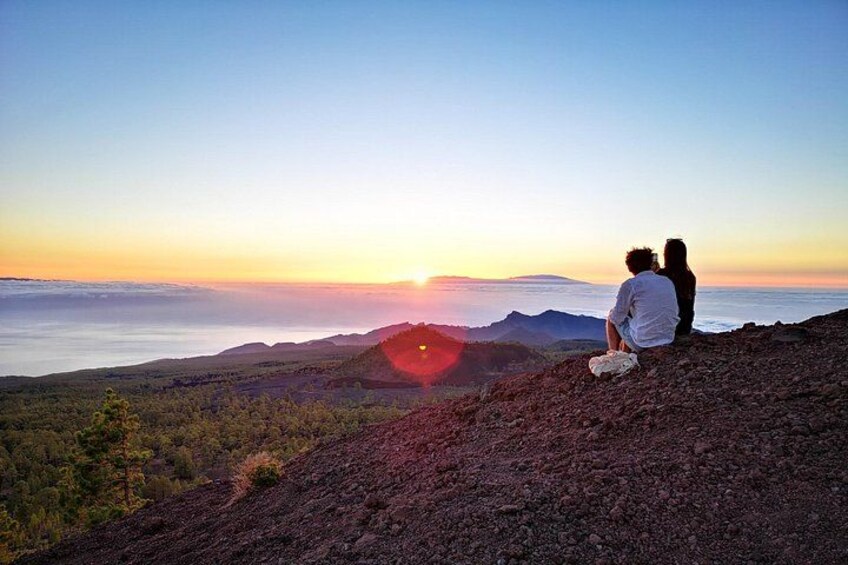 Una pareja sentada en una colina con vistas a un valle al atardecer. 2