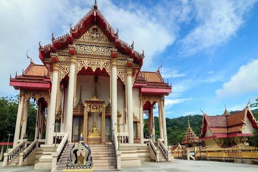 A temple with a red roof, golden decorations, and a golden statue. 2