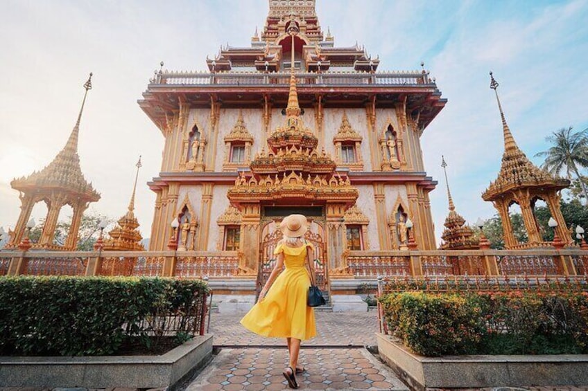 A woman in a yellow dress standing in front of a temple with ornate architecture. 1