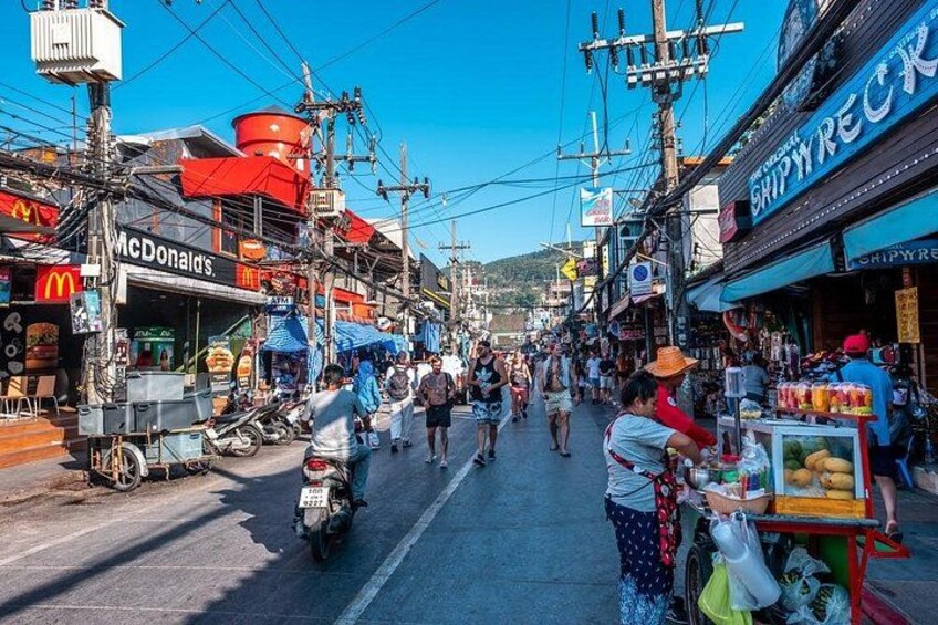 A bustling street with food stalls, a McDonald's, and a shop named 'The Original Shipwreck'. 3