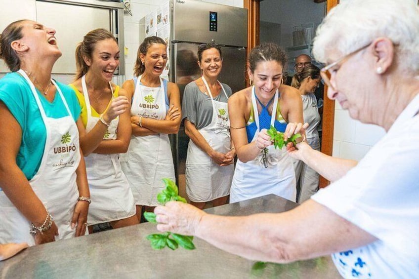 A group of people in a kitchen, some wearing aprons with 'UBBIPO' logos, engaged in a cooking activity. 4