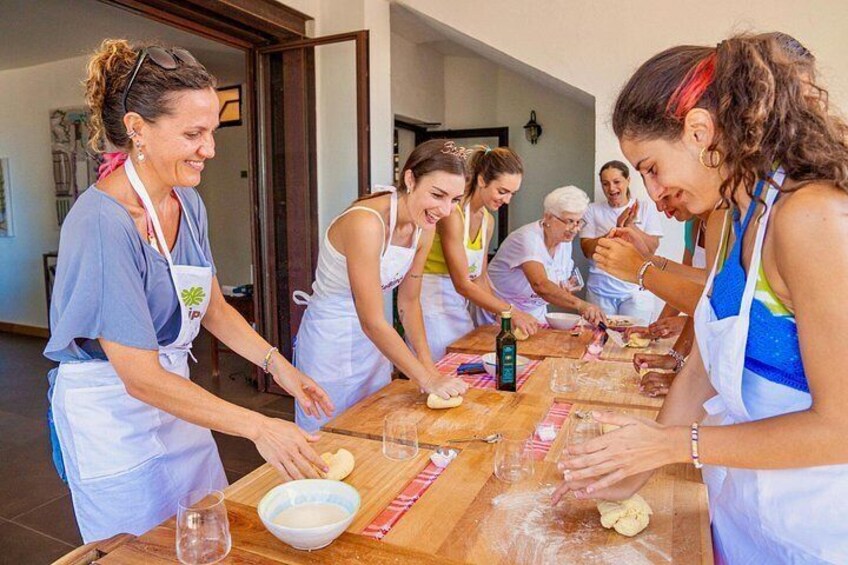 A group of people engaged in a cooking activity, with a wooden table, bowls, and ingredients. 1