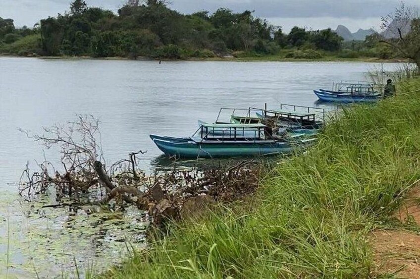 A calm river with boats docked along the shore, surrounded by greenery and trees. 3