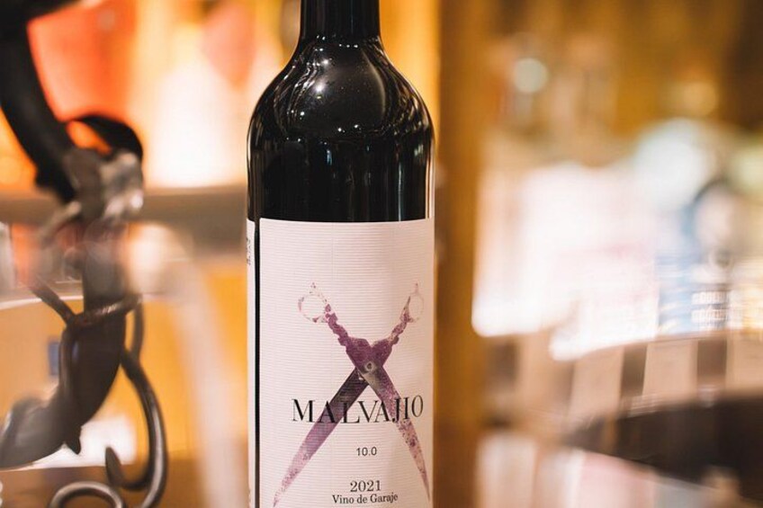 En flaska Malvasio-vin med en etikett som har ett lila motiv. 4