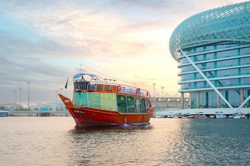 Un barco rojo con cabina verde y techo azul, amarrado cerca de un edificio moderno con una estructura de vidrio esférica. 1