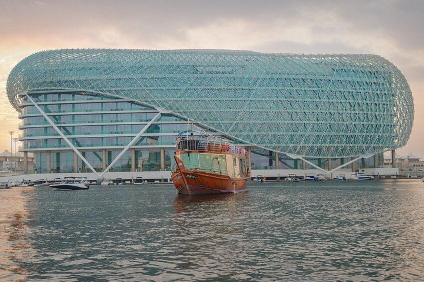 Un edificio moderno de arquitectura con un diseño curvo distintivo, un barco en primer plano y una masa de agua tranquila. 5