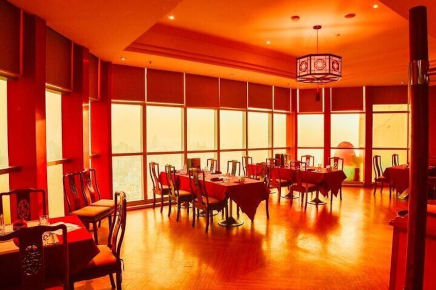 Un ristorante con pareti rosse, ampie finestre, pavimento in legno e tavoli apparecchiati per la cena. 3