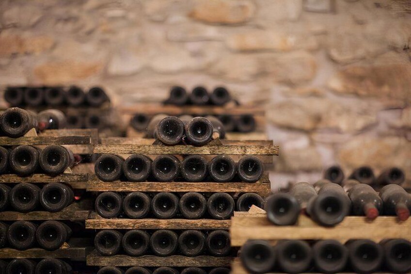 Stacks of wine barrels in a cellar with stone walls. 4