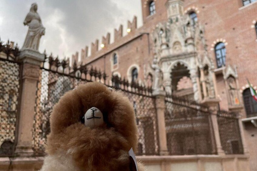 A teddy bear with a clock face in front of a historic building with intricate architecture. 4