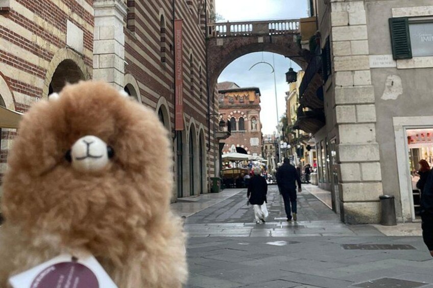 A street with a brick building, a stone archway, and a person walking. 5