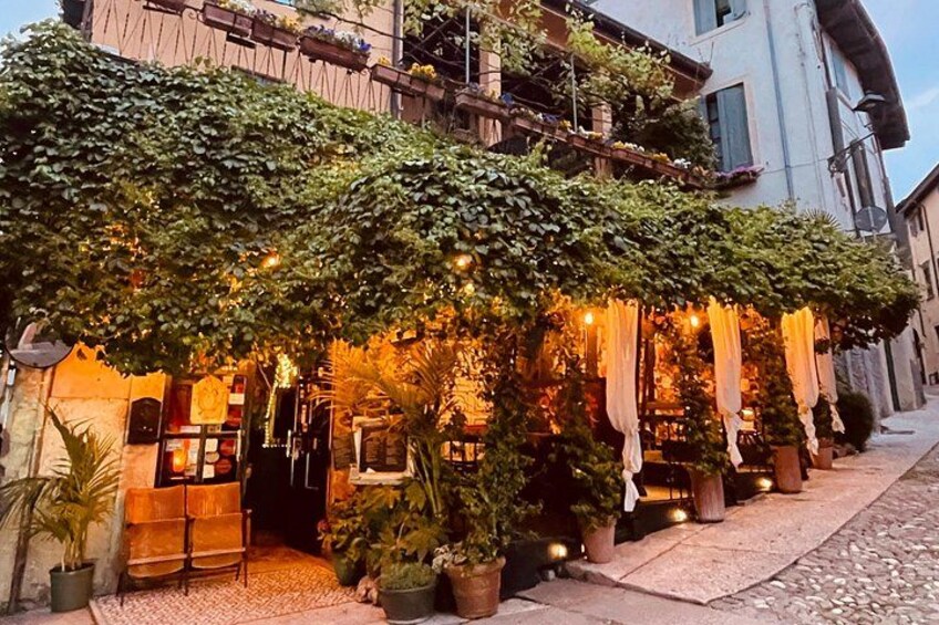 A restaurant with ivy-covered walls, outdoor seating, and string lights. 2