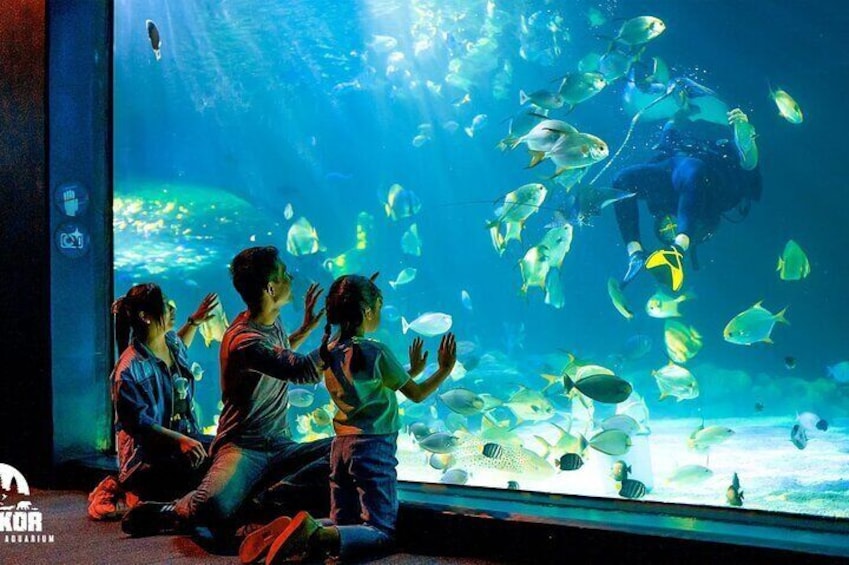 Ein Aquarium mit einem Taucher und Kindern, die Fische beobachten. 1