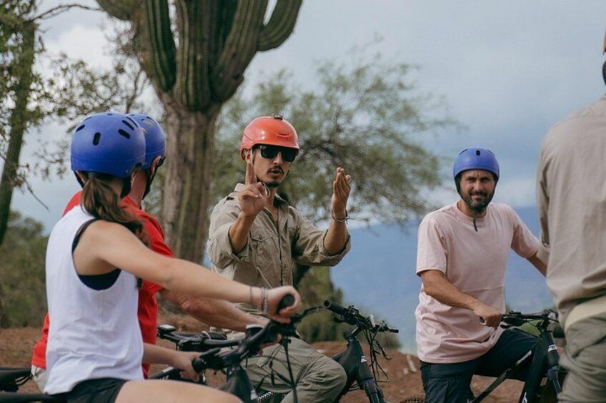 Un groupe de personnes à vélo, portant des casques, dans un cadre extérieur avec des arbres et un ciel dégagé. 1
