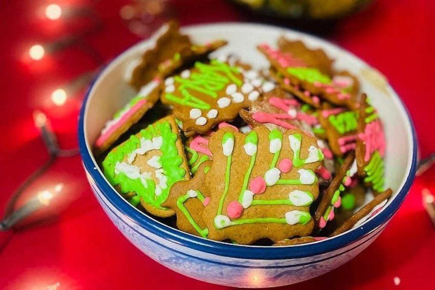 Un tazón con galletas de jengibre decoradas, con glaseado verde y confites rosas. 1