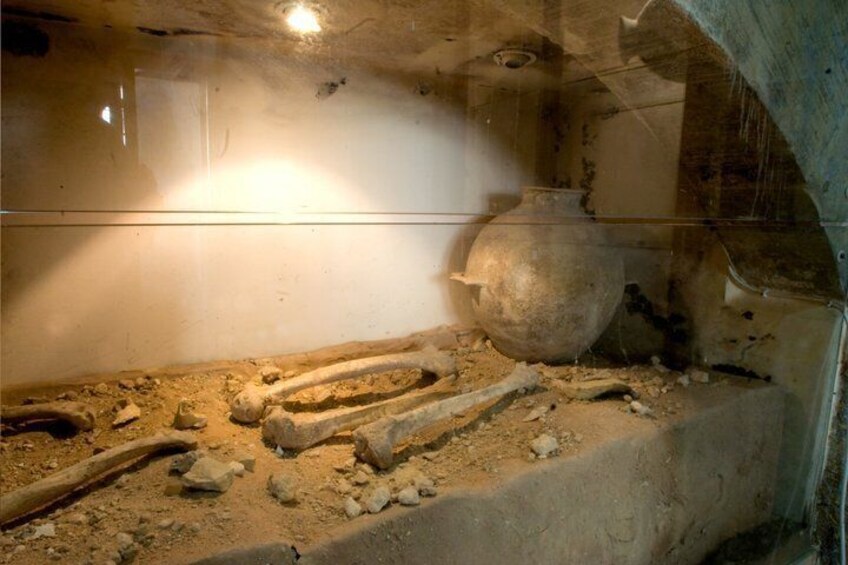 Een archeologische opgraving met zichtbare skeletresten en aardewerk. 5